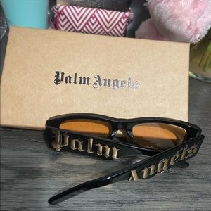 Palm Angels sunglasses. Frames are black with gold Palm Angels,lenses are orange